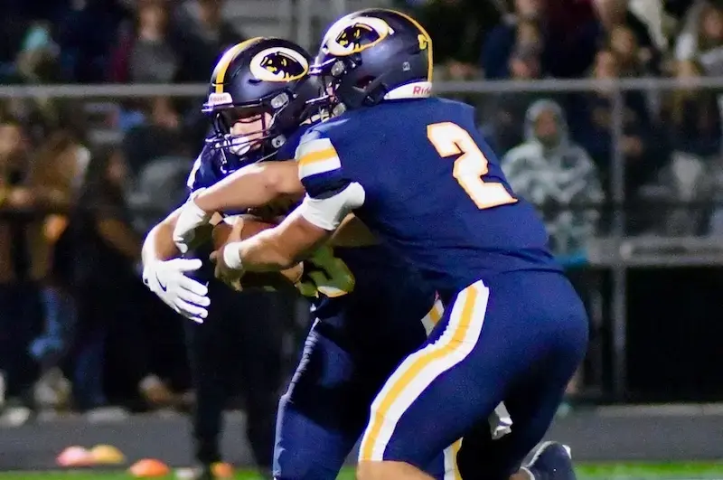 Dewitt quarterback handing ball off in week 7 of Michigan High School Football